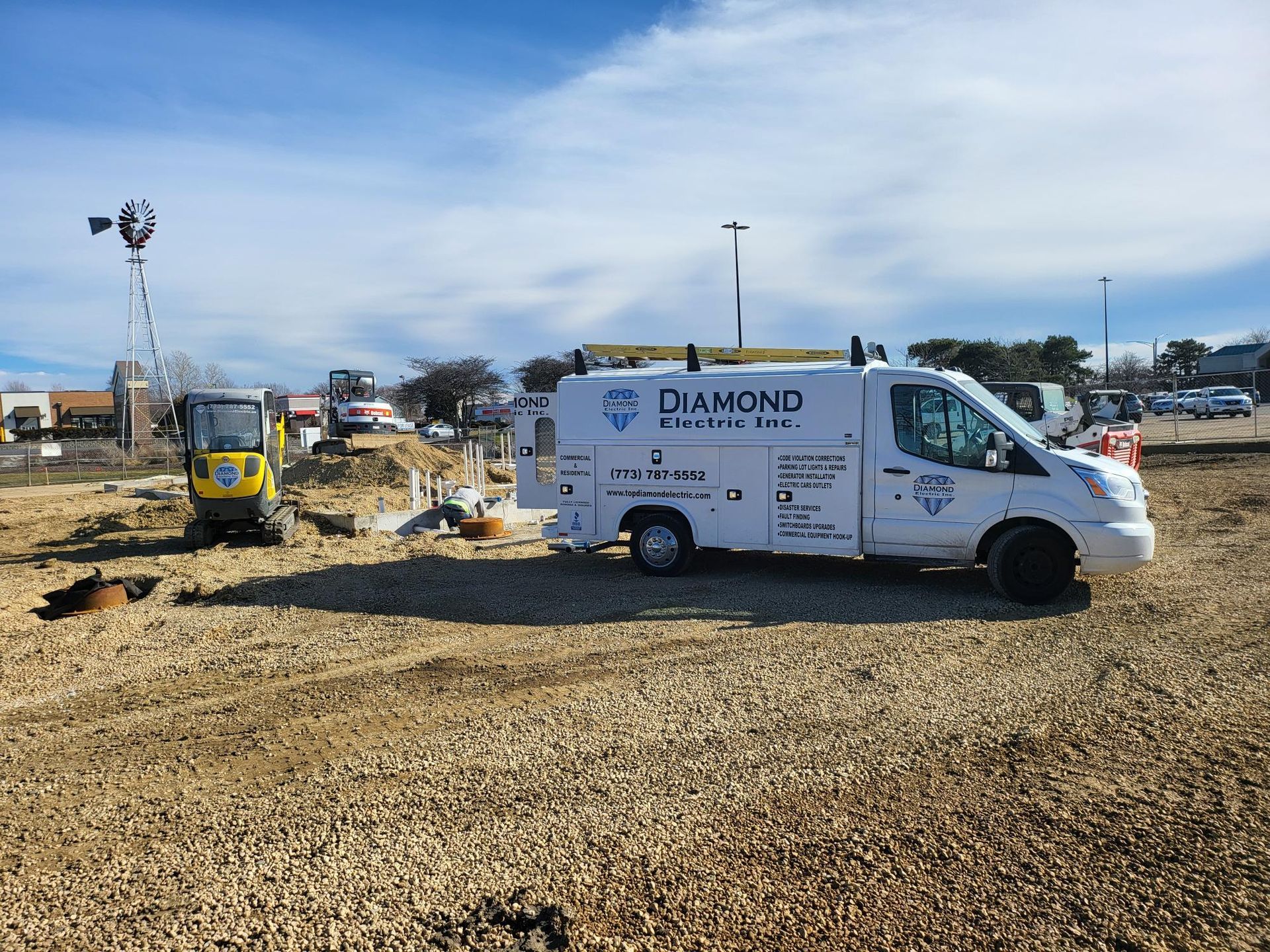 A white diamond van is parked in a gravel lot.