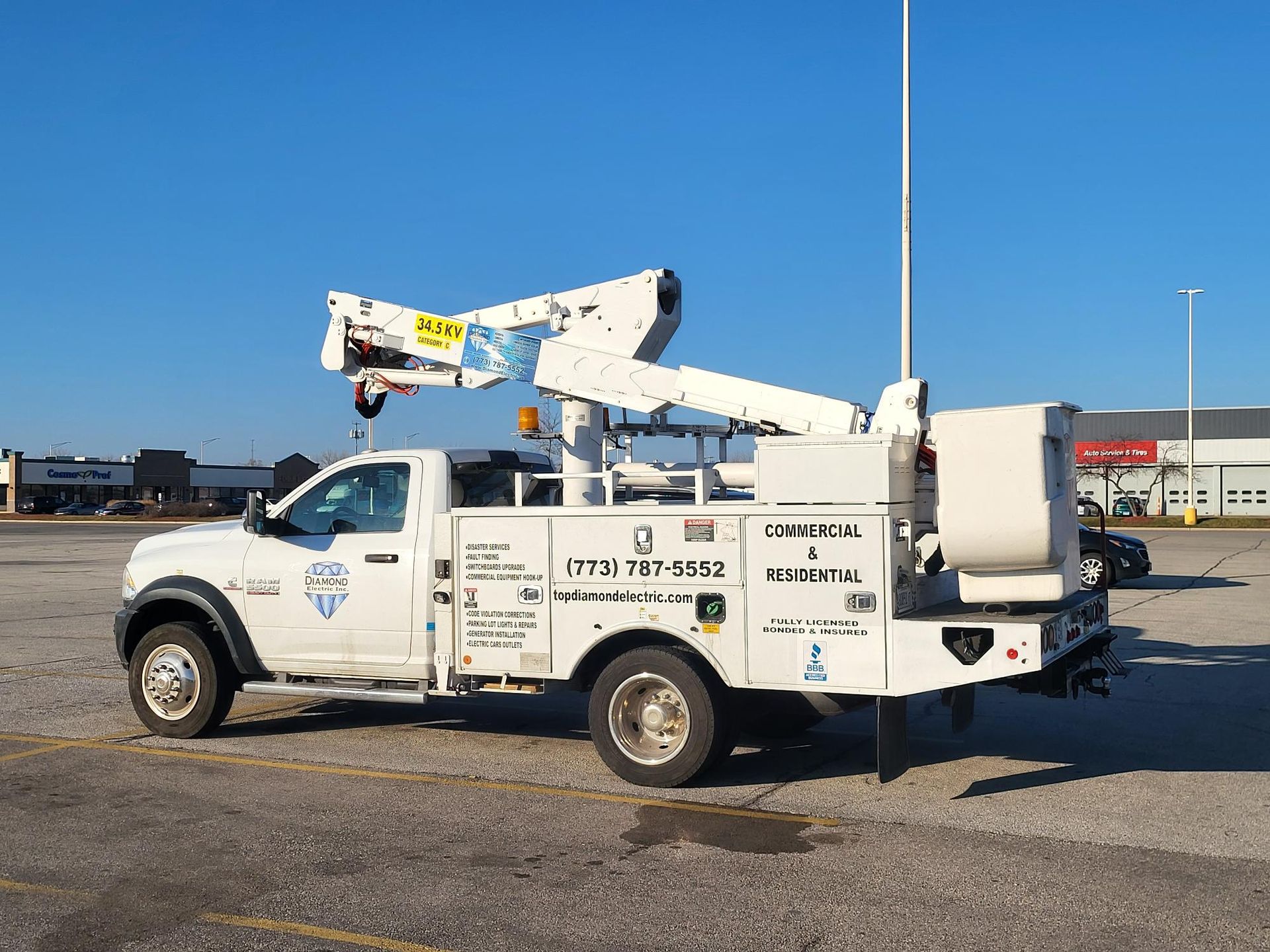 A white truck with a crane on the back is parked in a parking lot.
