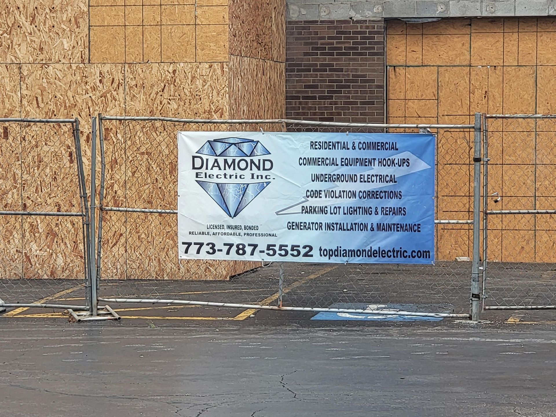 A sign for diamond electric inc. is on a fence