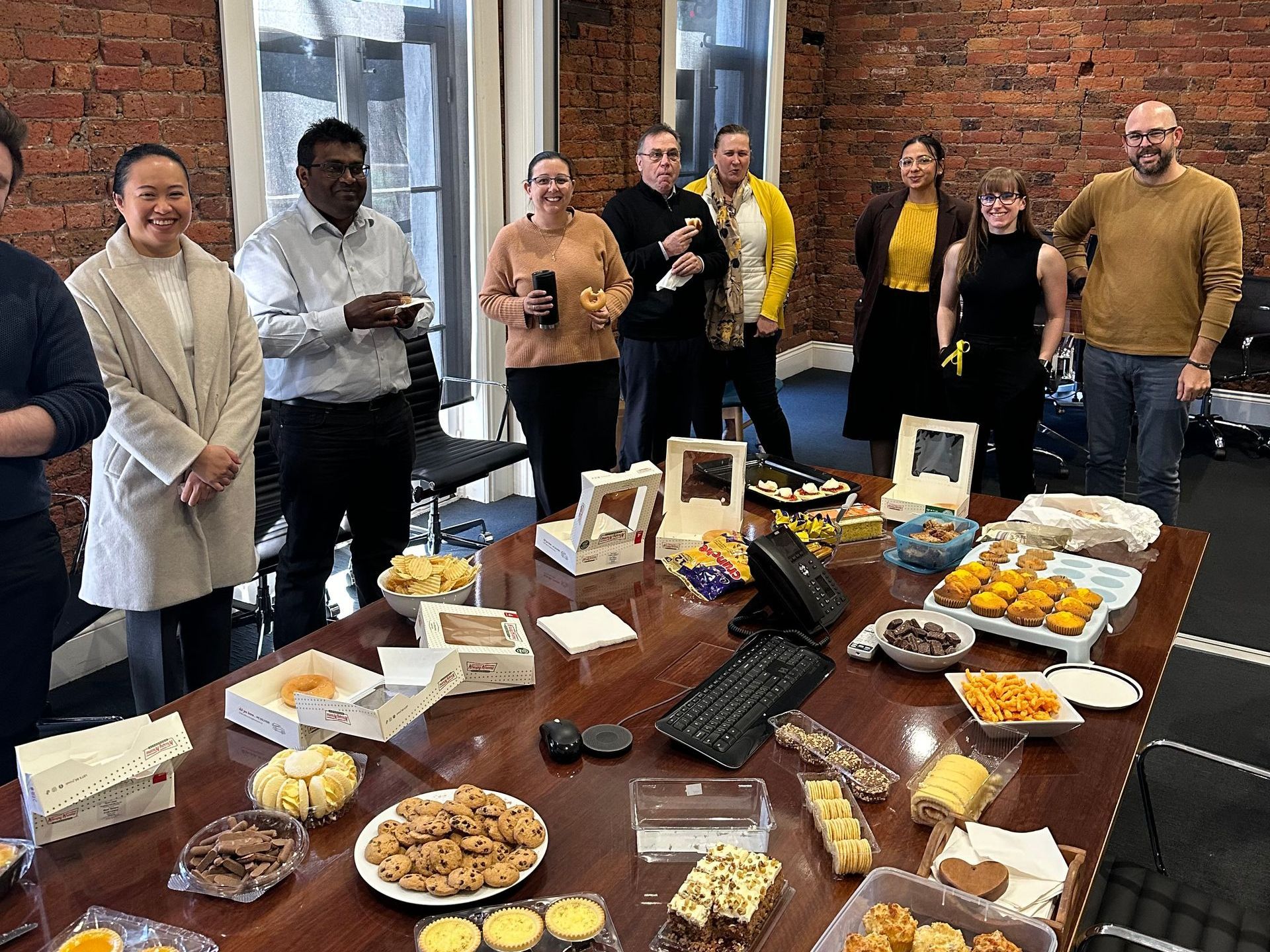 A group of people are standing around a table filled with food.