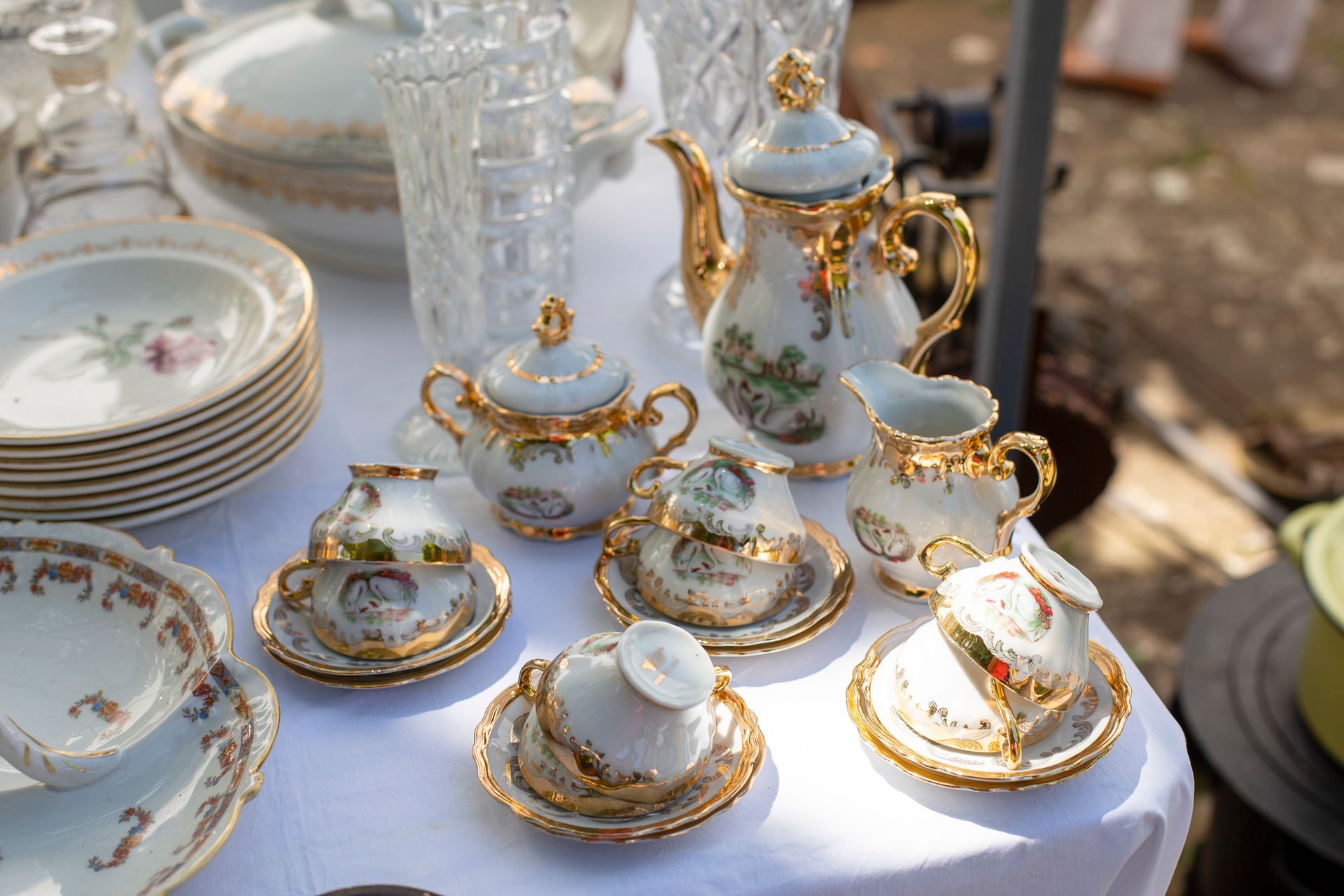 A table topped with plates , cups , saucers , and vases.