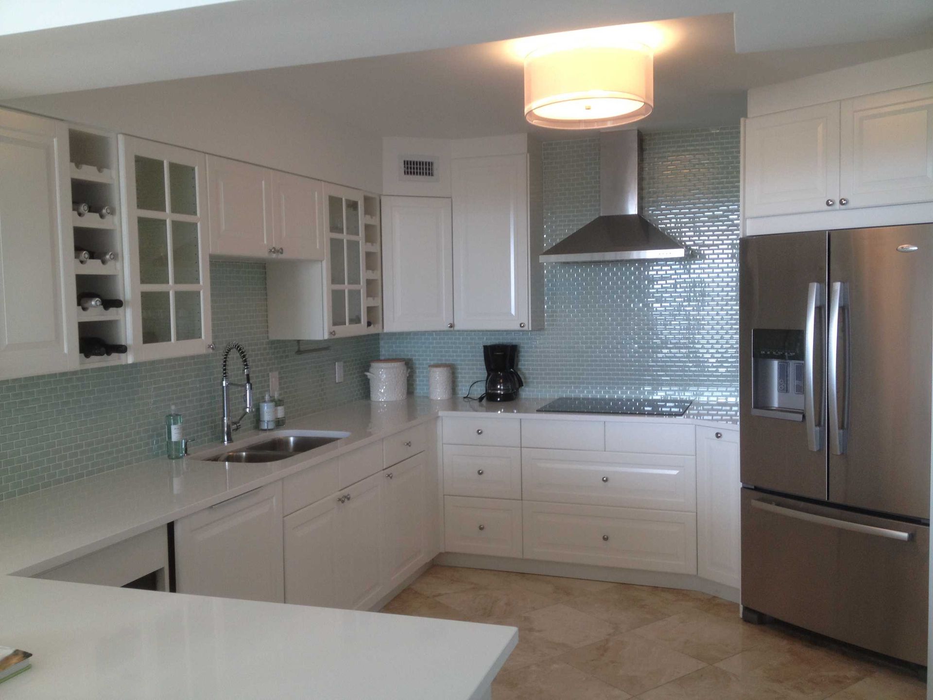 White kitchen with dark countertops, mosaic backsplash, and white cabinets and appliances
