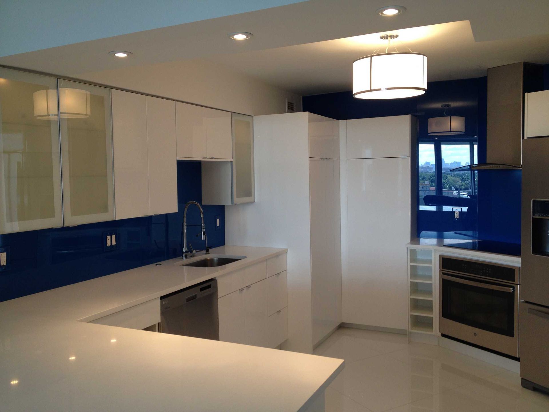 Modern white kitchen with blue backsplash, built-in appliances, and an island countertop