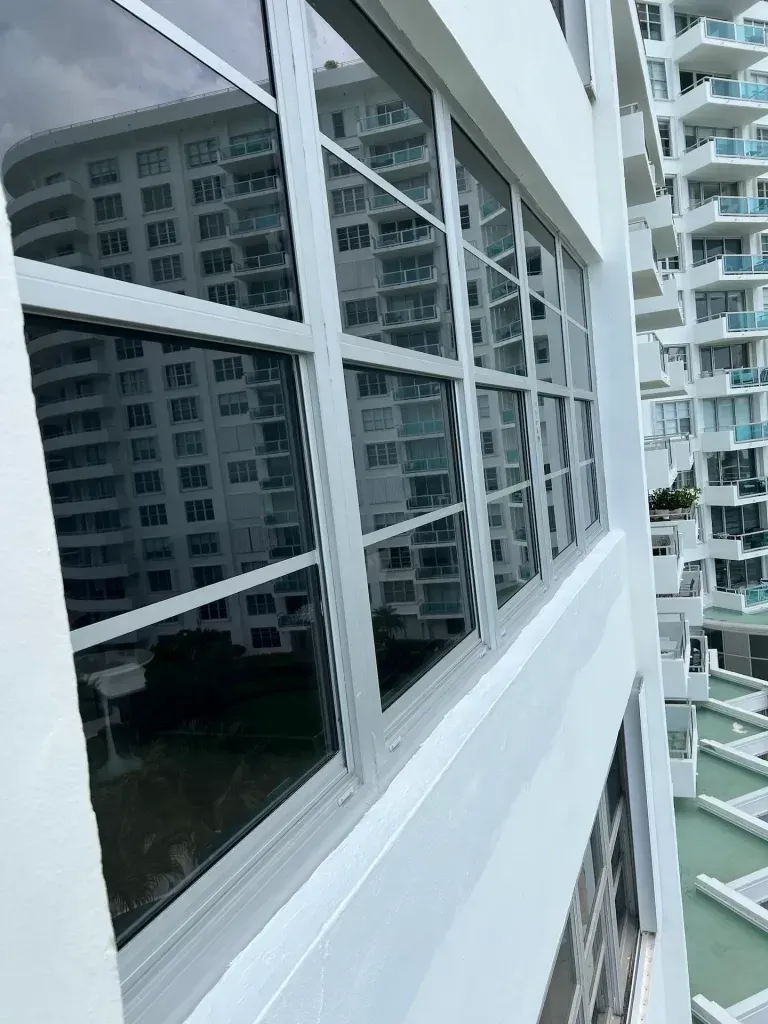 Exterior view of a high-rise building from a balcony, showing reflective windows and neighboring apartments