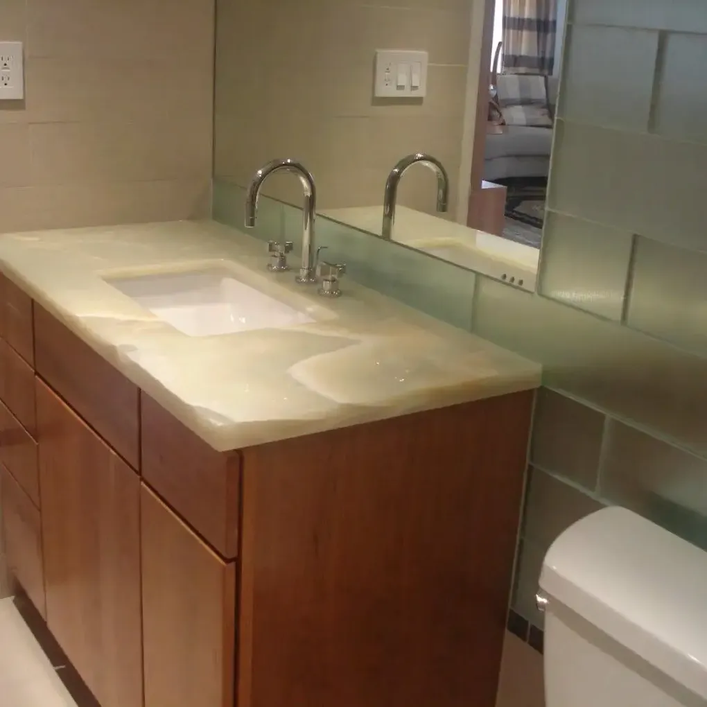 Bathroom vanity with double sink, wood cabinets, beige countertop, mirror, and toilet.