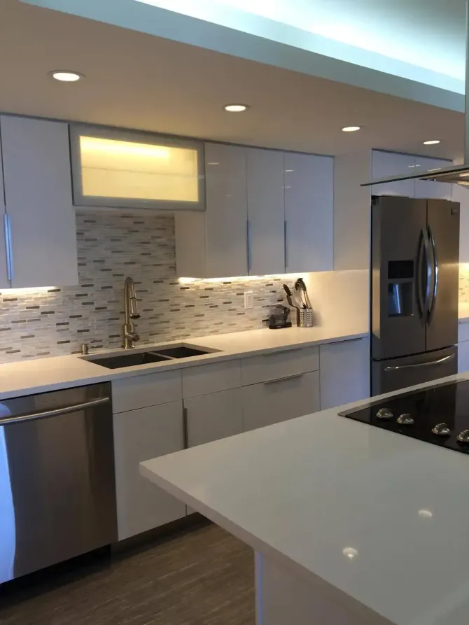 Modern kitchen with light cabinets, stainless steel appliances, and a large island under recessed lighting