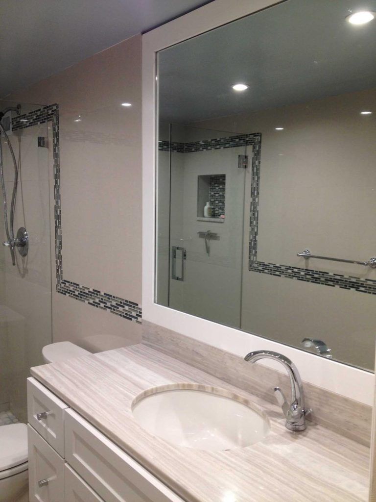 Bathroom vanity with large mirror, white sink, and wall-mounted soap dispenser.