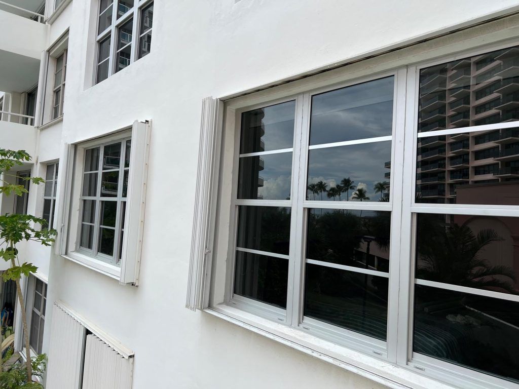 White apartment building exterior with several windows and white shutters, viewed from the side