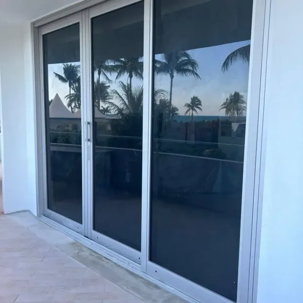 Sliding glass doors reflecting palm trees and a blue sky on a patio