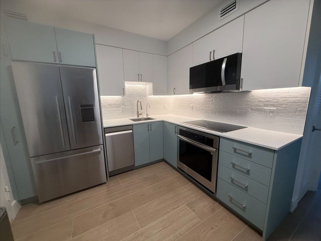 Modern kitchen with stainless appliances, white cabinets, and blue lower cabinets