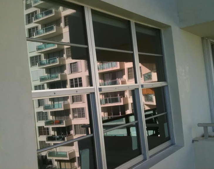 Balcony view of apartment buildings reflected in large window panes