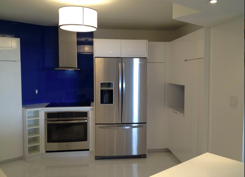 Modern kitchen with blue accent wall, stainless steel refrigerator, oven, and white cabinets