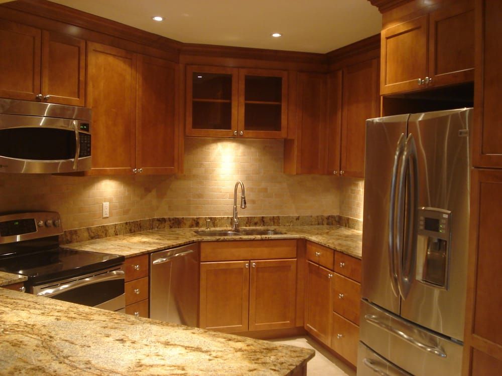 Warm kitchen with wood cabinets, granite countertops, stainless steel appliances, and recessed lighting.