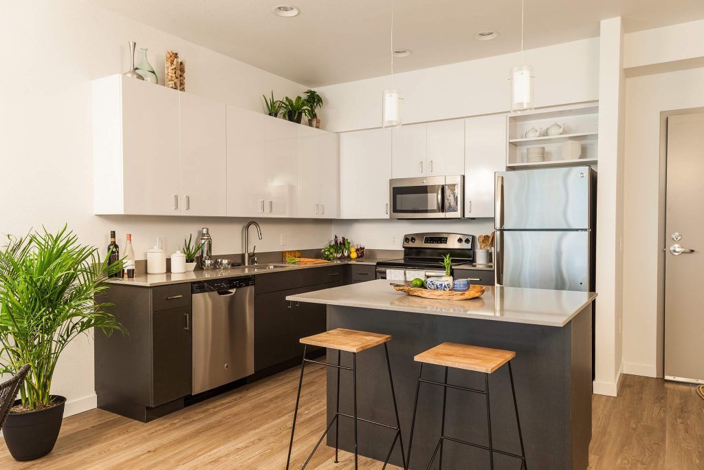 Modern kitchen with white cabinets, black island, stainless appliances, and two stools