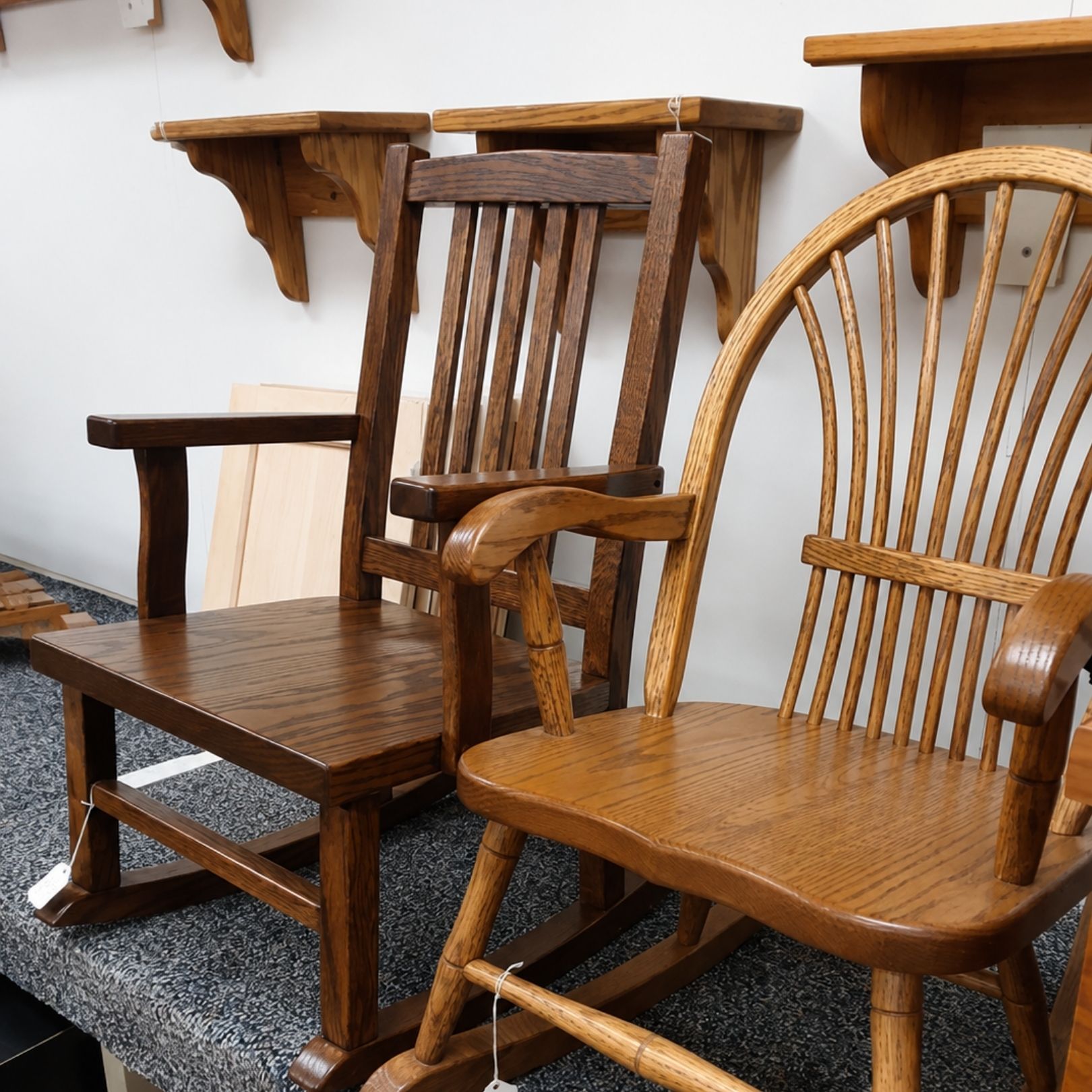 Assorted wooden chairs on a rug beside a wall shelf in a room