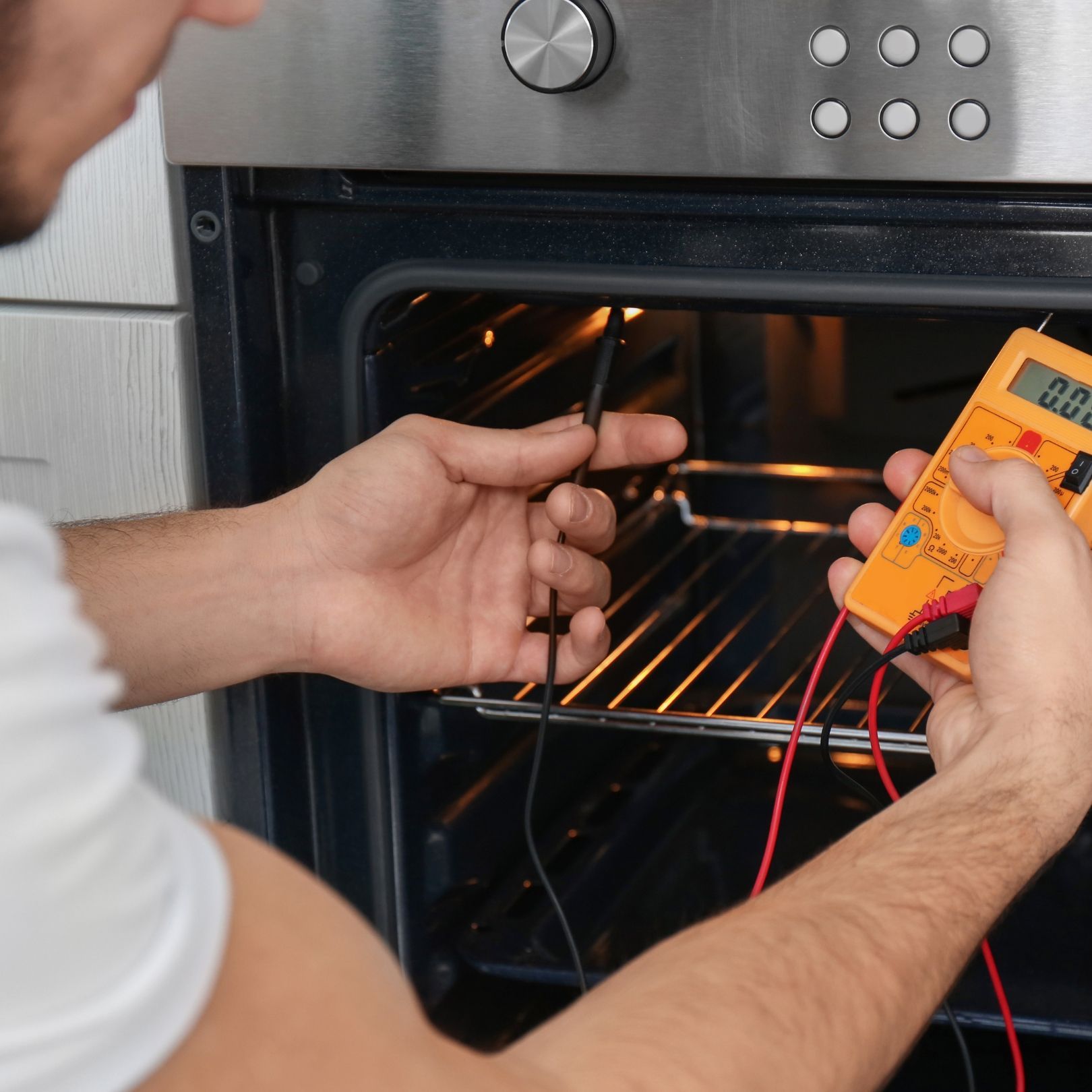 Person testing an oven with a multimeter and probe
