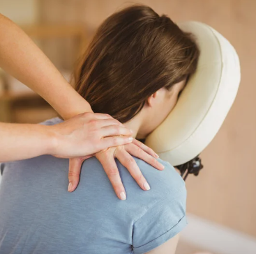 Een massagetherapeut kneedt de schouders van een cliënt .
