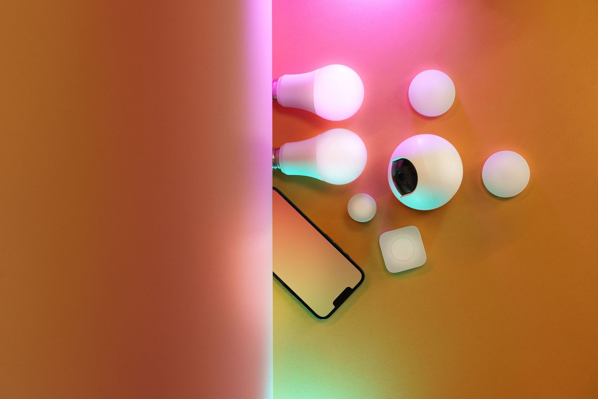 Abstract colorful arrangement of white round objects and a tilted phone on a warm orange-pink background