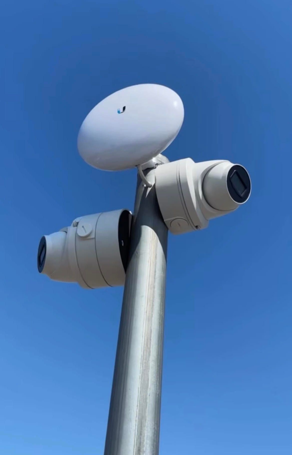 Cluster of surveillance cameras mounted on a pole against a blue sky