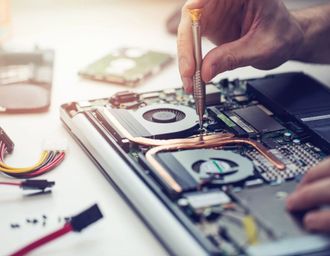A Person is Fixing a Laptop Computer With a Screwdriver — Coastal Computing Solutions in Taree, NSW