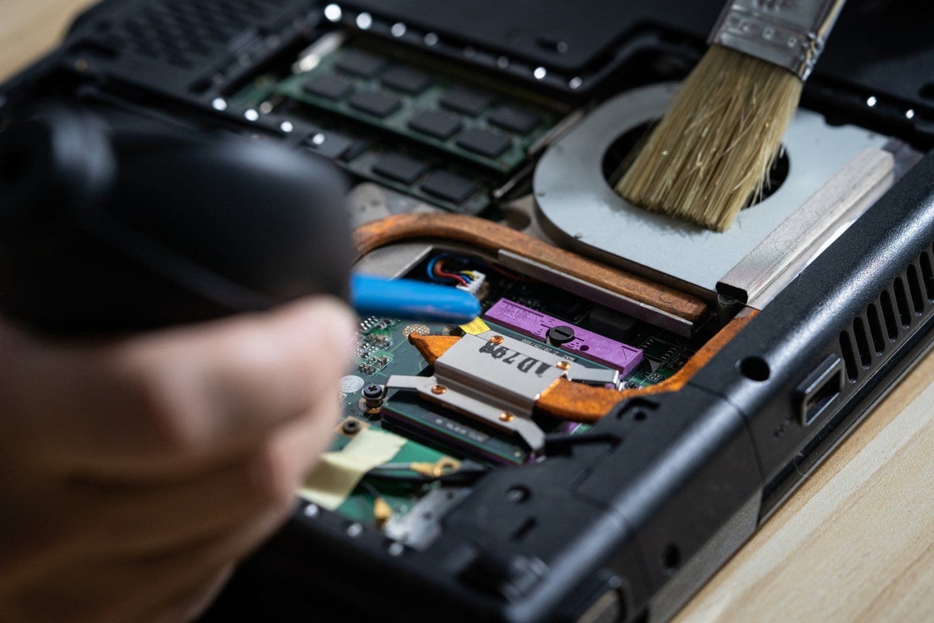 A Person is Cleaning a Laptop With a Brush — Coastal Computing Solutions in Taree, NSW