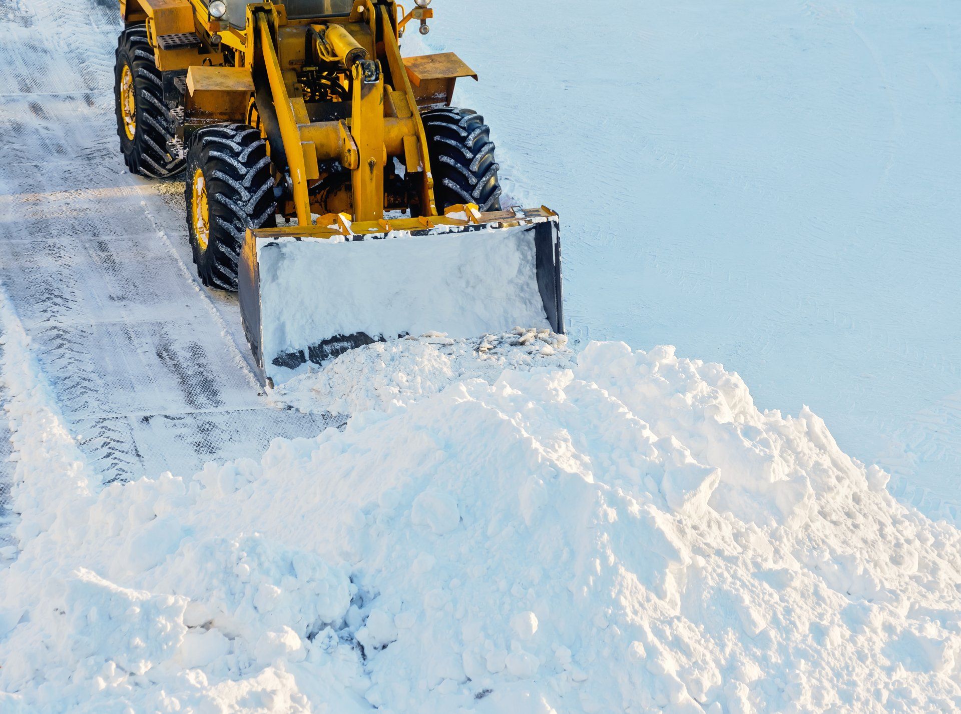 Un chasse-neige jaune déblaye la neige d'une route.