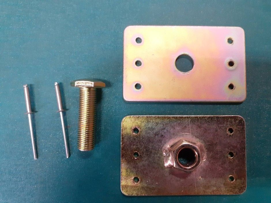 Two small metal pins, a bolt, and two rectangular metal plates with holes on a blue surface