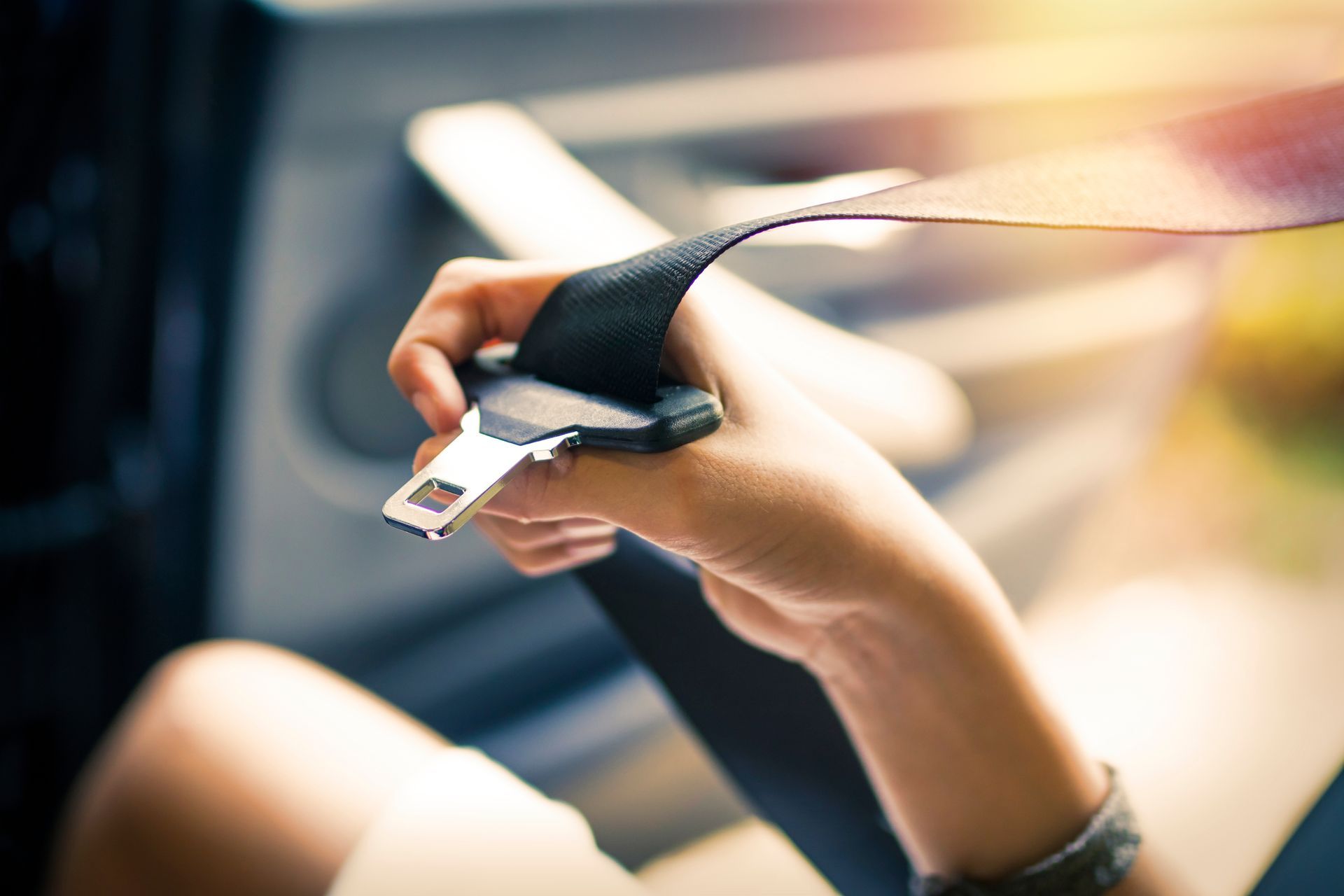 A close-up view of a hand buckling a black car seat belt in a vehicle.