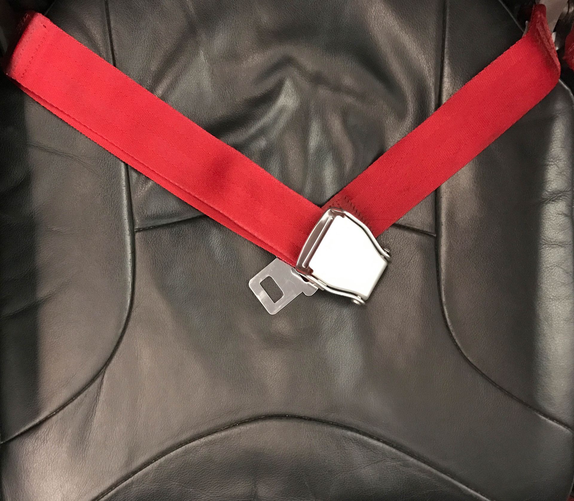 A seat belt fastened over a black leather seat.