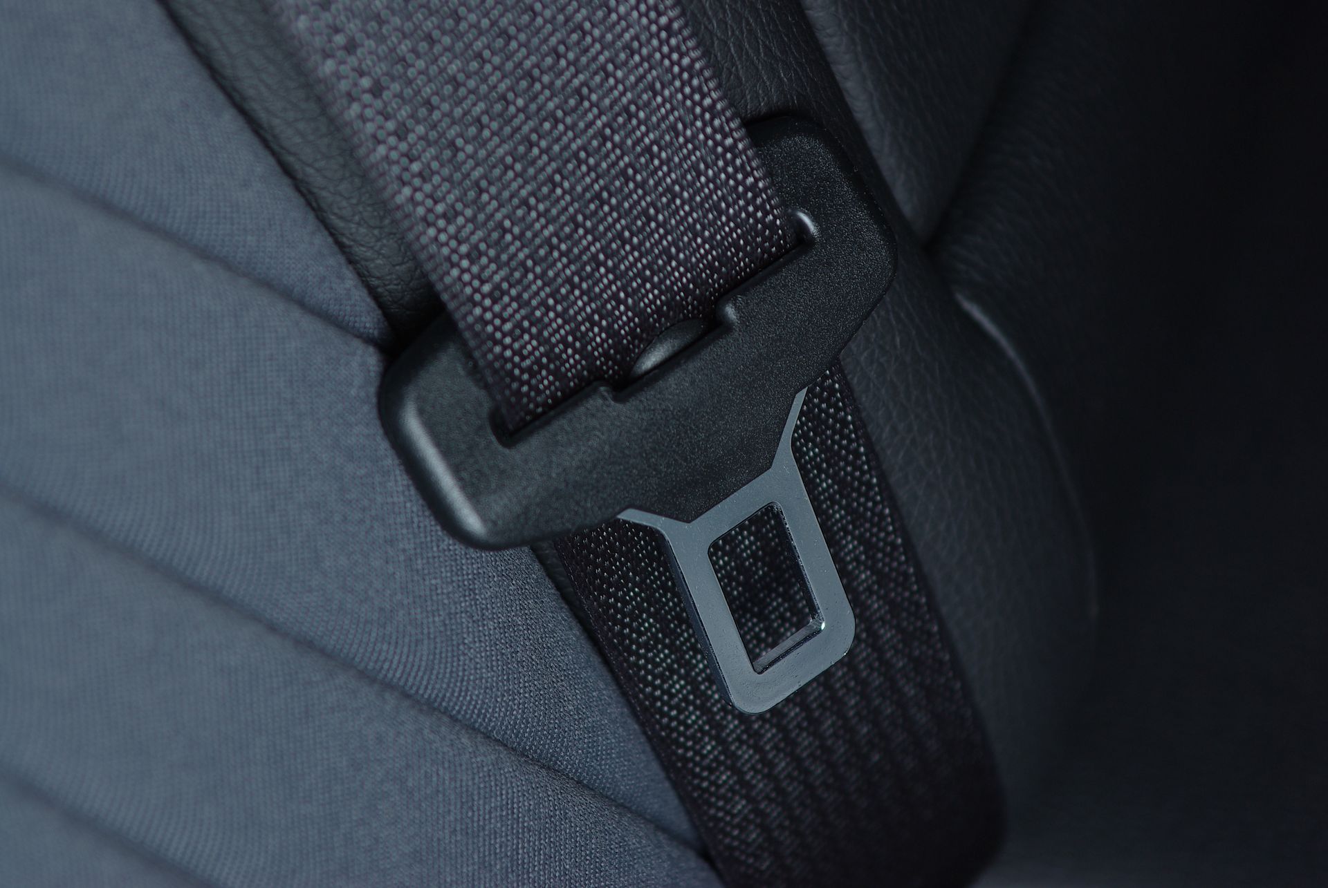 Close-up of a black seatbelt buckle attached to a dark, textured car seat.
