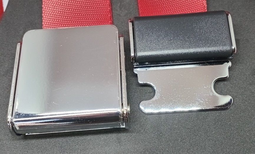 Two red seat belt straps with one silver and one black metal buckle clasp side by side