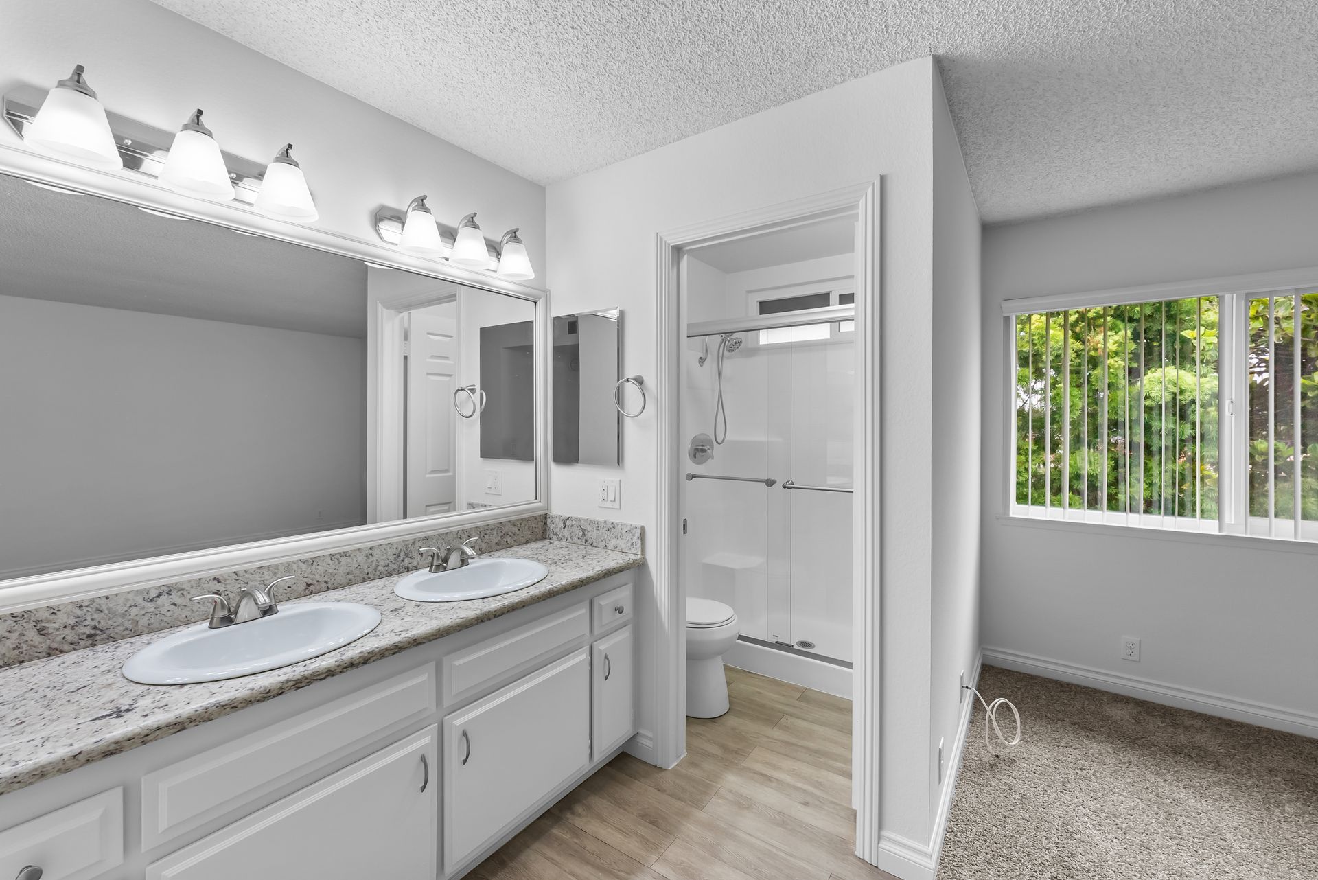 bathroom with mirror and view into smaller room with toilet