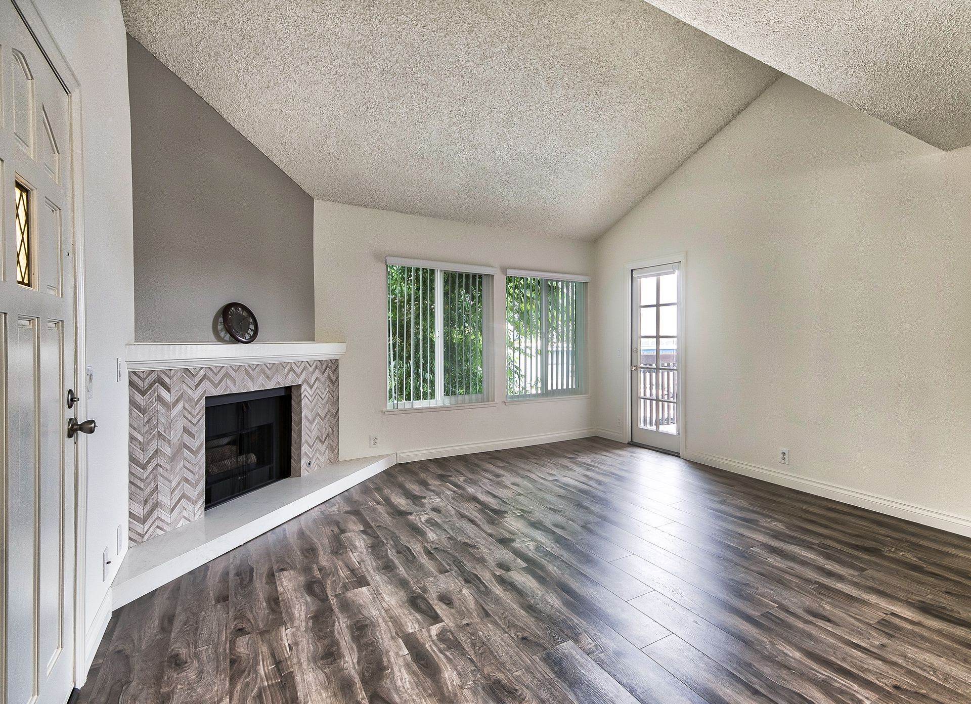 An empty living room with hardwood floors and a fireplace.