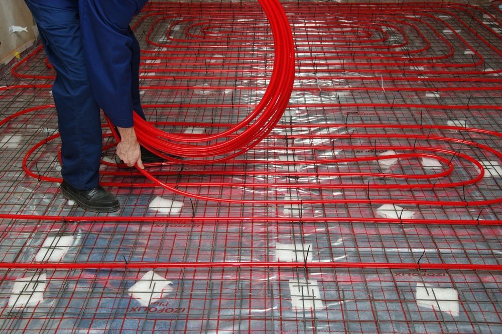 Person Installing Red Radiant Floor Heating — Illawarra Underfloor Heating In Ulladulla, NSW