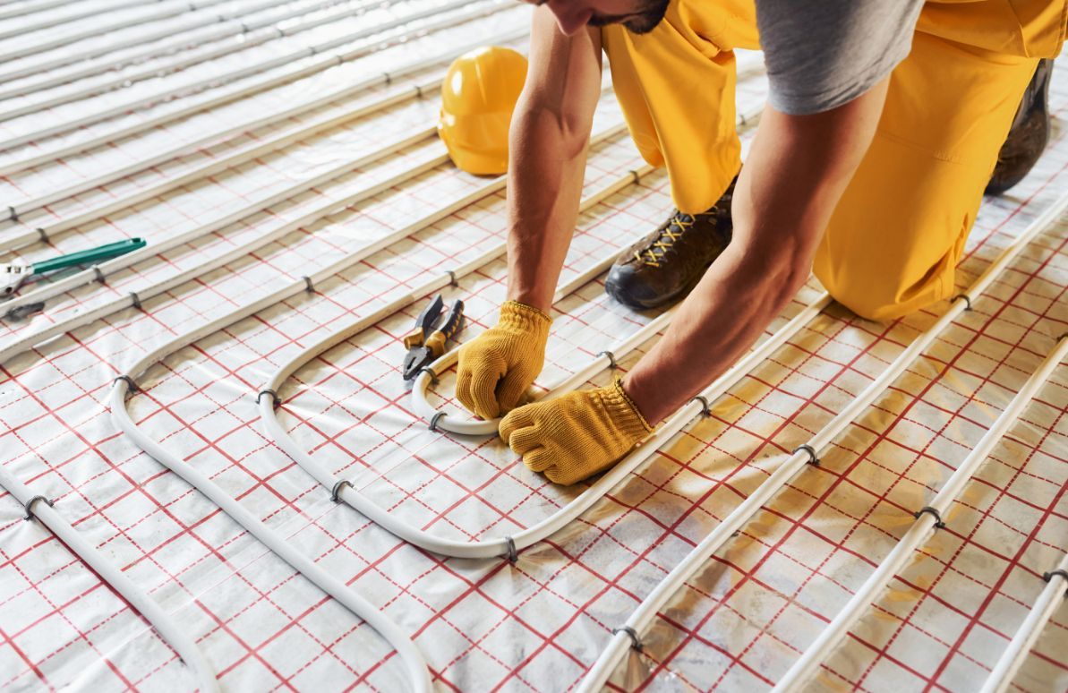 Man in Yellow Work Clothes Installs Underfloor Heating Tubes — Illawarra Underfloor Heating In Kiama, NSW
