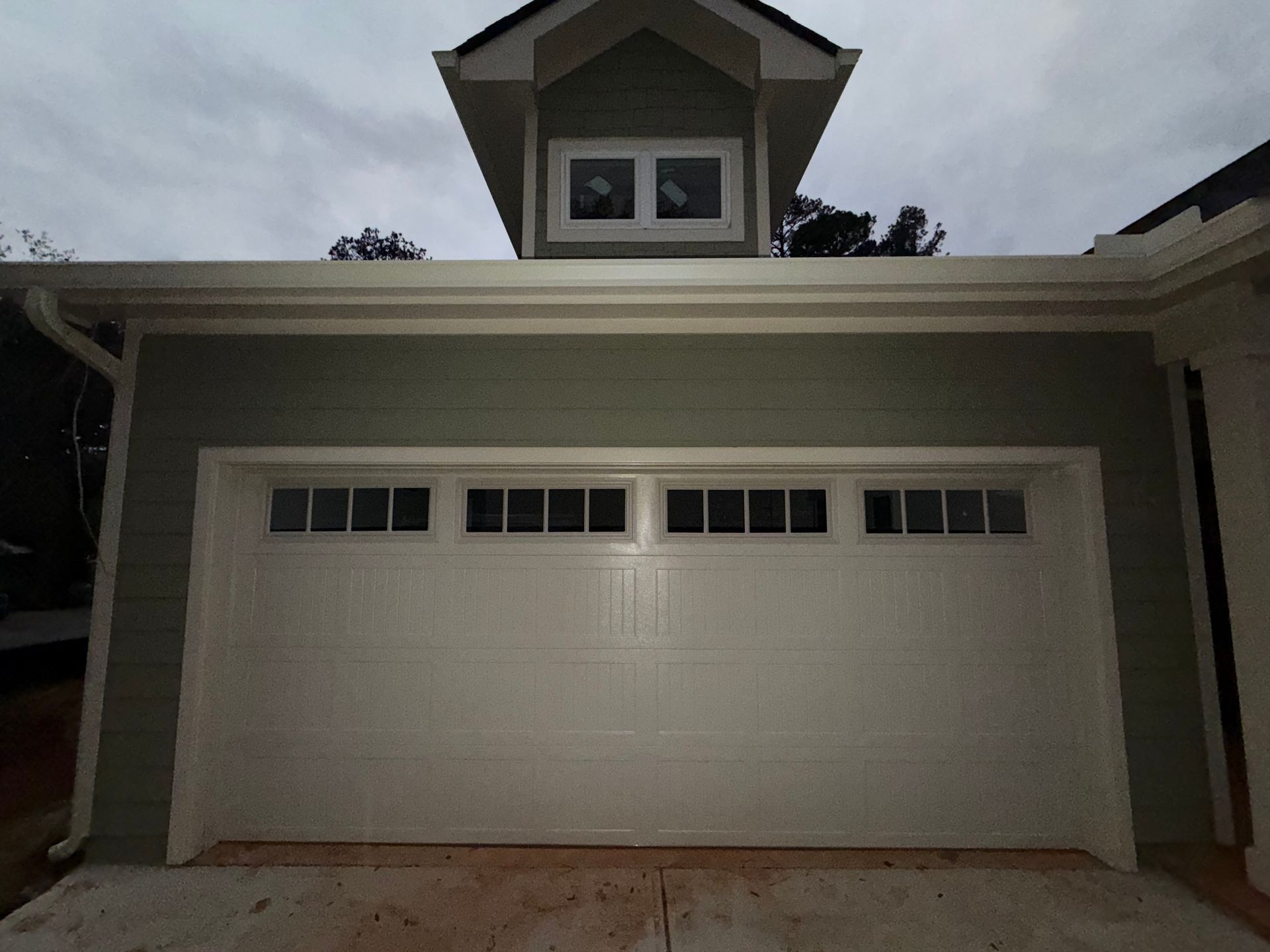 Two-car garage door on a house exterior with a small dormer window above.