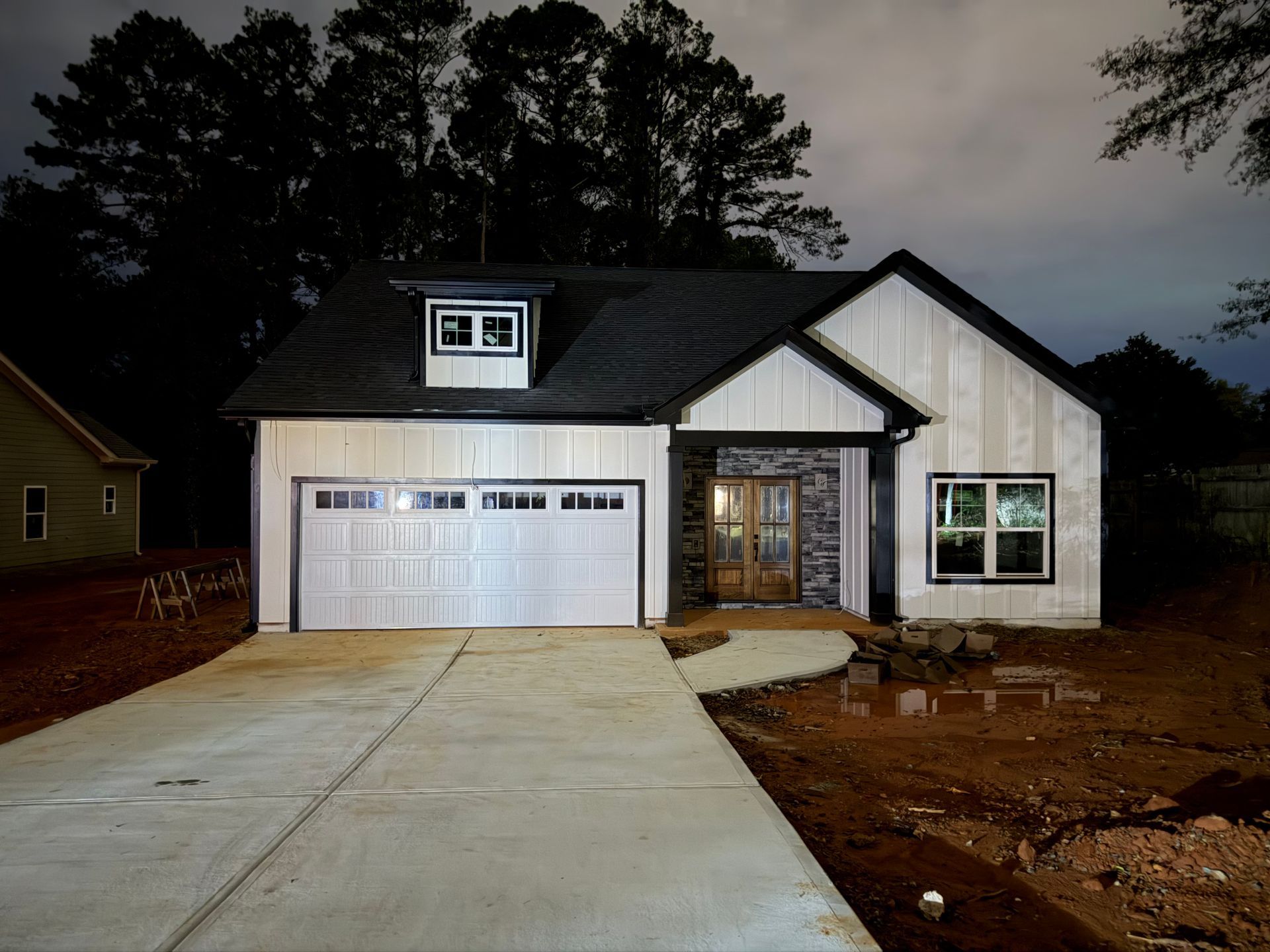 New white suburban house with a two-car garage and concrete driveway at dusk
