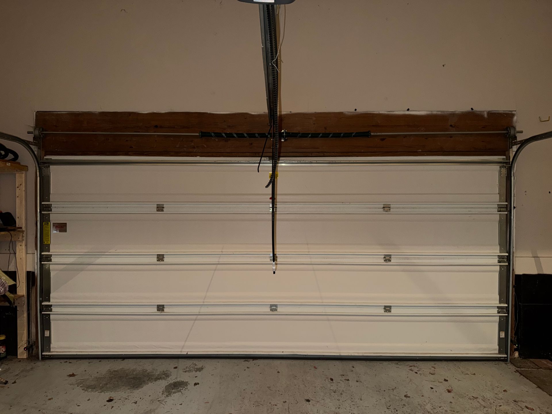 White garage door with horizontal panels in a dimly lit garage interior.