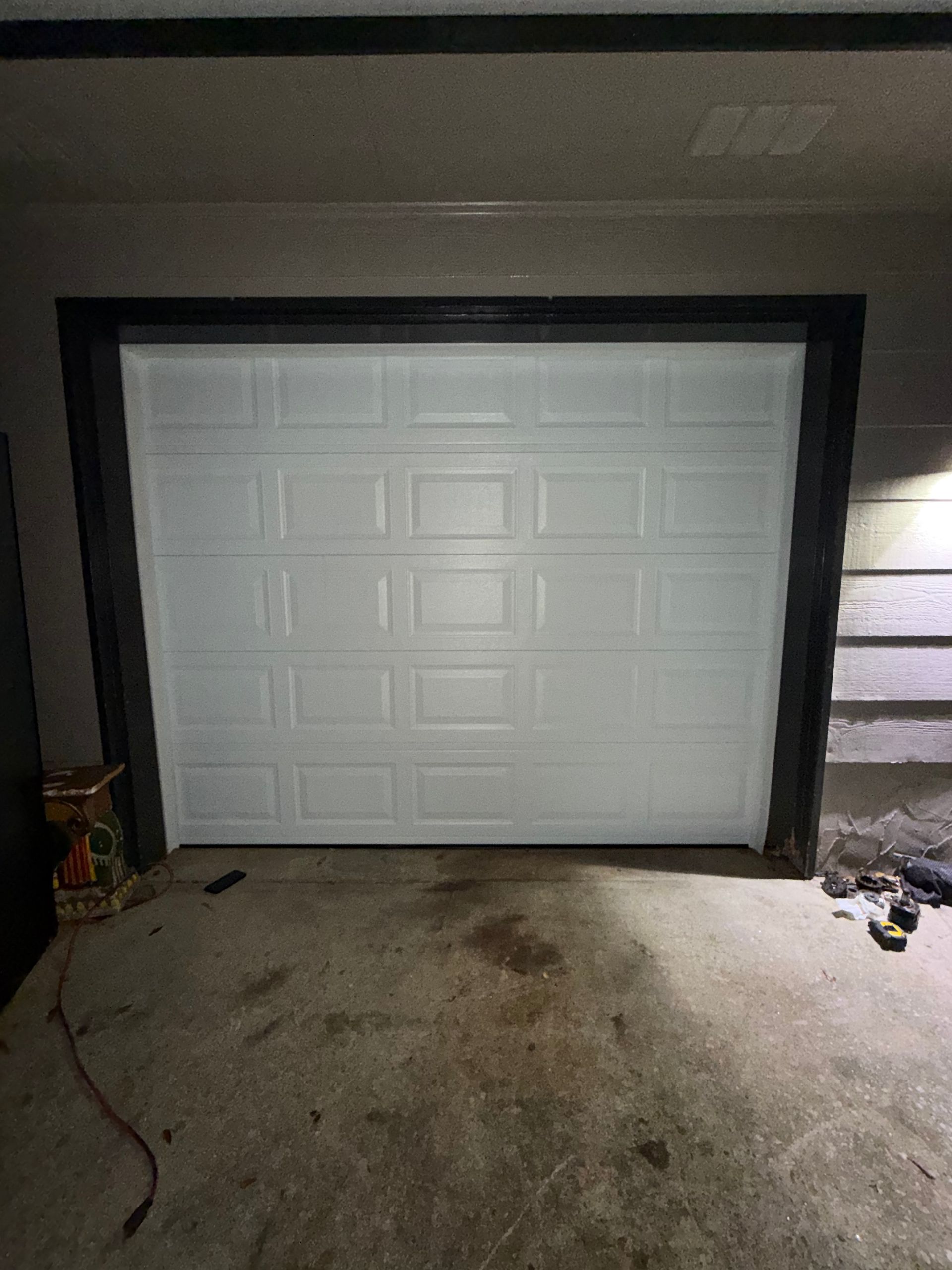 Closed white garage door in a dimly lit driveway at night