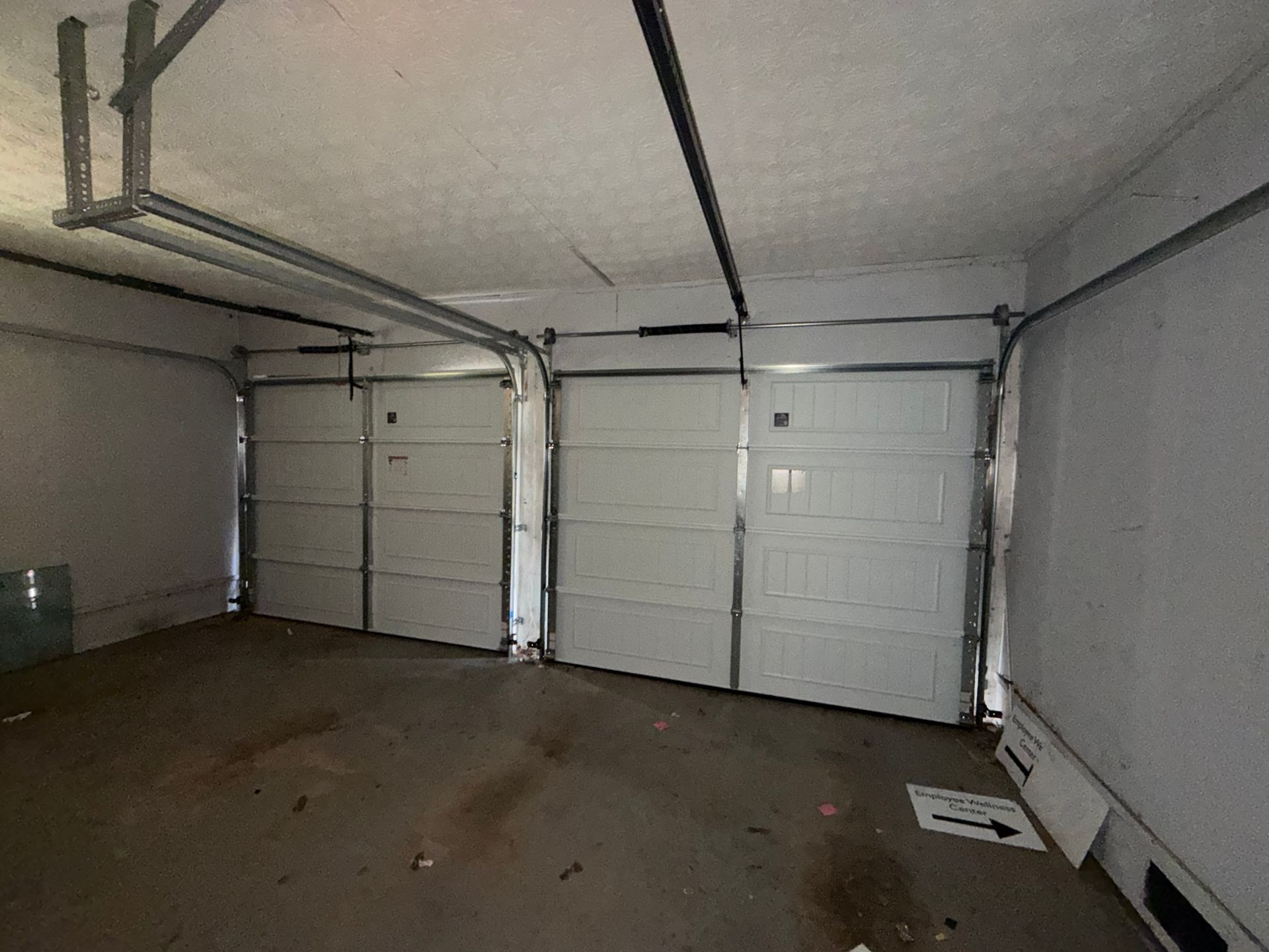 Empty garage with two white overhead doors and a concrete floor