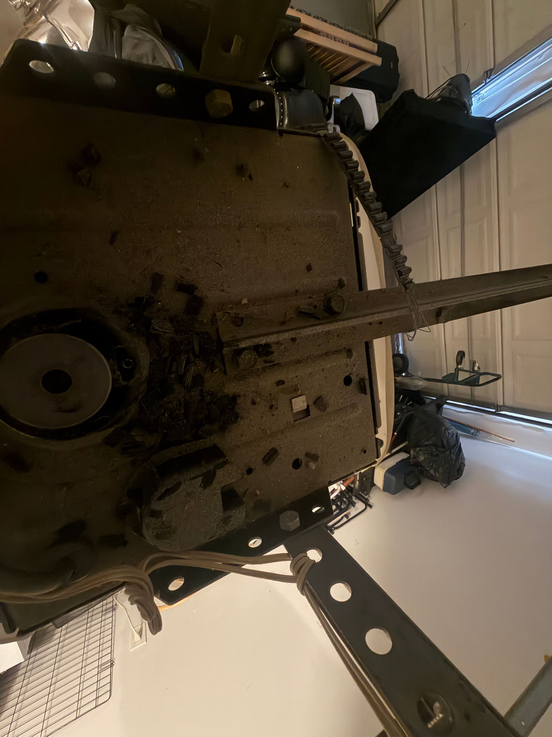 Underside of a metal machine or appliance with wires and mounting brackets, viewed from below.