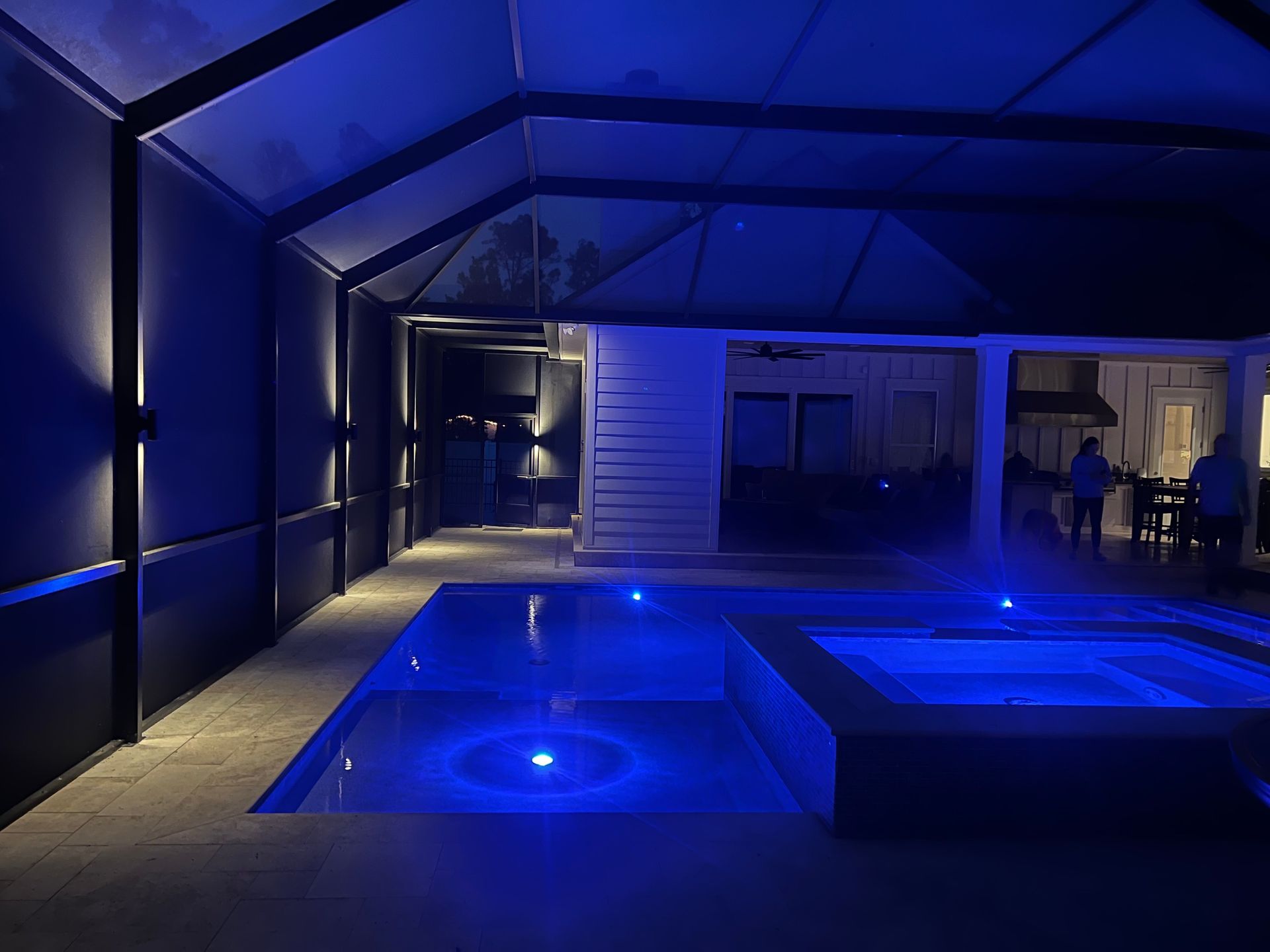Pool area lit with blue lights at night.
