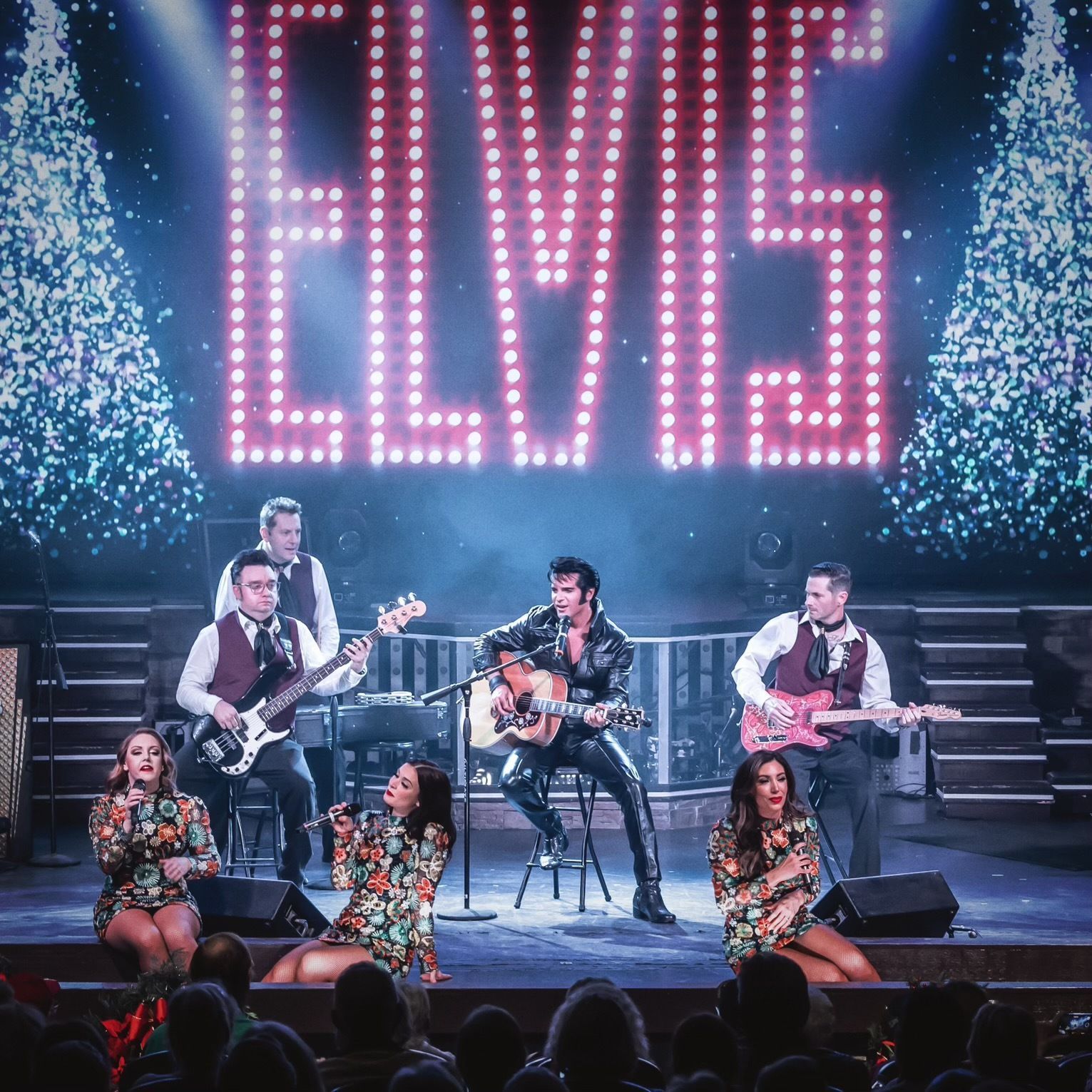 A live band performs a Christmas-themed Elvis tribute show on stage with a large 