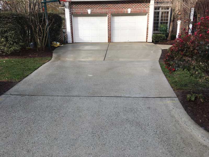 Residential driveway leading to a double garage, with a steep concrete slope and landscaped sides