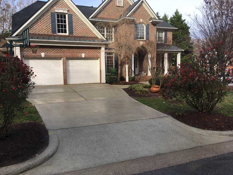 Suburban brick house with two-car garage, driveway, and landscaped front yard