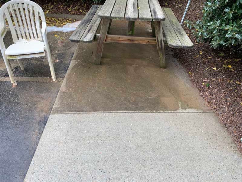 Concrete path leading to a picnic table with a white chair beside it outdoors