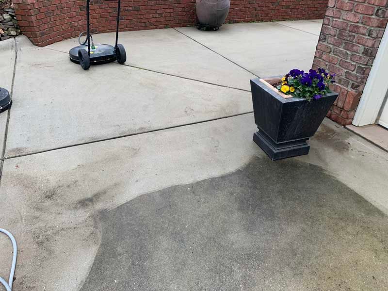 Concrete patio by a brick wall with a scooter and a black planter of purple flowers