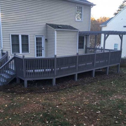 Backyard wooden accessibility ramp with railings attached to a beige house