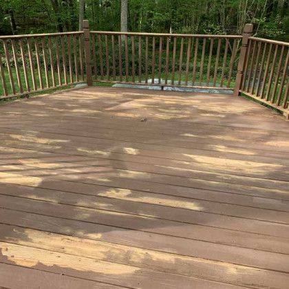 Wooden deck with railings overlooking a wooded yard in daylight