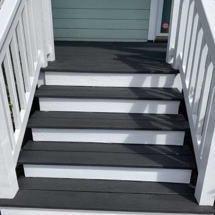 White porch stairs with dark gray treads and railings leading to a house entrance